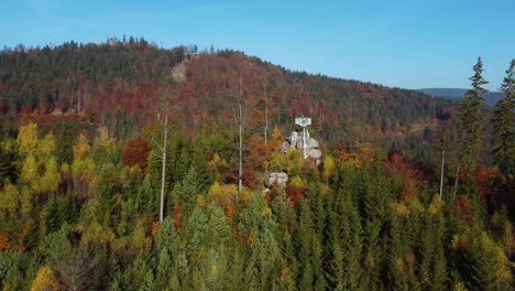 lookout-tower-on-a-rock-in-an-autumnal-mixed-forest,-sunny,-orbit