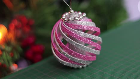 Pink-and-silver-glitter-foam-christmas-ornament,-on-a-green-cutting-mat