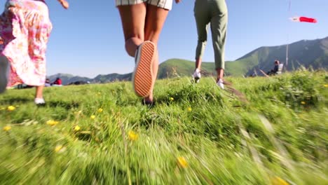 Slow-motion-follow-shot-of-family-running-on-green-meadow-during-sunny-day---Low-angle-track-shot---Georgia,Kazbegi