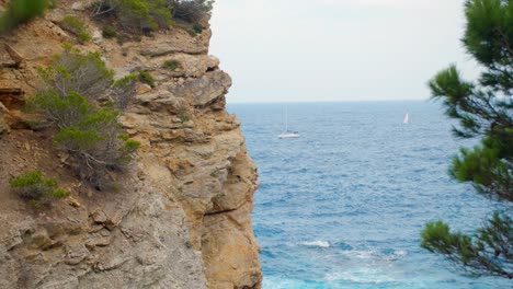 Rocky-cliffs-and-beautiful-blue-sea-seen-from-the-coastal-path-with-a-boat-passing-by