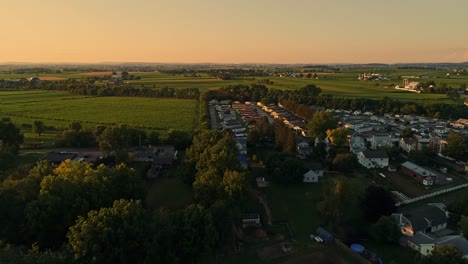 Eine-Luftaufnahme-Von-Amish-Farmen-Und--Feldern-Und-Einem-Mobilen,-Hergestellten,-Modularen-Hauspark-Während-Der-Goldenen-Stunde-An-Einem-Spätsommernachmittag