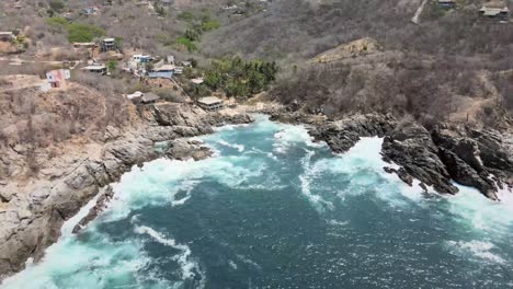 Pull-back-above-small-beach,-with-view-of-cliffs-in-Oaxaca,-Mexico