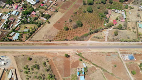 Hermosa-Antena-De-Motos-Conduciendo-Por-Carretera-Cerca-De-Un-Pequeño-Pueblo-En-Kenia