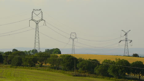 Hilly-landscape-during-a-sunny-day-of-a-field-of-meadows-and-power-poles