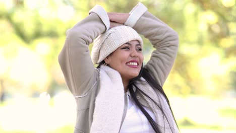 Girl-dressed-warmly-during-the-autumn-fall-season-raises-her-hands-in-complete-bliss-and-happiness-at-a-park