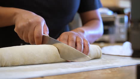 Slicing-raw-dough-roll-into-cinnamon-rolls-for-baking---isolated-slow-motion