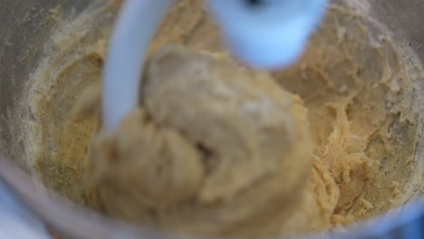 Straight-down-close-up-view-of-dough-being-mixed-with-a-dough-hook---slow-motion-macro-view