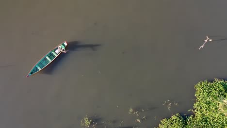 Aerial-view-of-fisherman-with-canoe-dropping-fishing-net-into-the-river