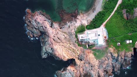 Bird's-eye-view-of-a-mansion-on-a-rocky-mountain-in-Hong-Kong-Cape-D'Aguilar-with-sea-waves