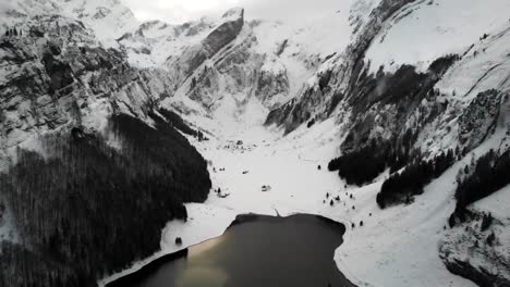 Luftüberflug-über-Den-Seealpsee-In-Appenzell,-Schweiz-Mit-Einer-Winterlandschaft-Voller-Schnee-Und-Blick-Auf-Felsen-Und-Gipfel-Des-Alpsteins