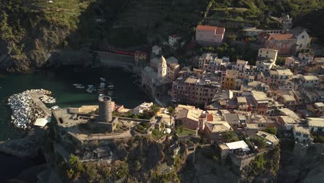 droneshot-forward-with-some-tilt-towards-italian-coastline-village-with-a-train-passing-true-at-sunrise-4k