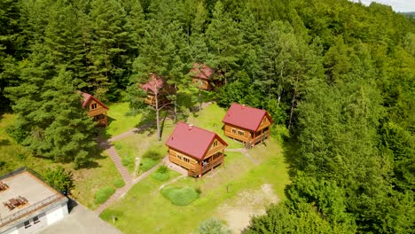 Aerial-shot-of-wooden-holiday-houses-in-forest-beside-Radunksie-Dolne-Lake-in-Poland,Borucino