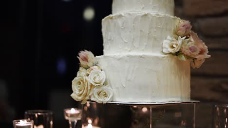 Beautiful-Three-Tiered-Wedding-Cake-With-Minimal-Edible-Flower-Decoration,-Surrounded-With-Candles-On-The-Table