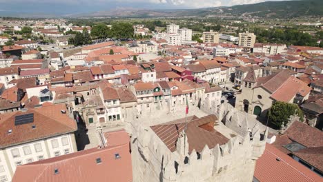 Aerial-flying-forward-Passing-Castle-tower-over-historic-downtown-buildings,-Chaves