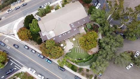 Top-Down-Aerial-view-of-an-outdoor-wedding-celebration-setup-with-white-chairs-on-a-green-lawn,-in-Rancho-Santa-Fe,-California