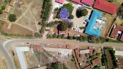 top-down-Aerial-of-colorful-rooftops-wit-parking-lot-in-a-small-Kenyan-town