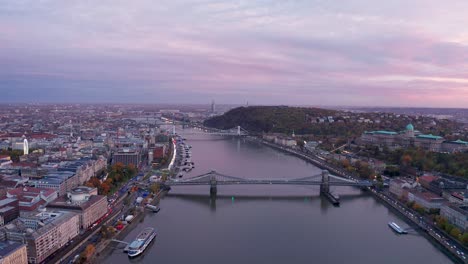 Majestic-aerial-view-of-budapest-hungary-over-danube-river-and-Széchenyi-Chain-Bridge-during-violet-and-pink-cloudy-sky