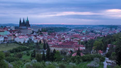 Night-to-day-sunrise-timelapse-in-Prague,-Czech-Republic-as-seen-from-Strahov-gardens-with-view-of-Prague-Castle,-Malá-strana-and-downtown-in-the-distance-as-the-morning-sunshine-lights-up-the-city