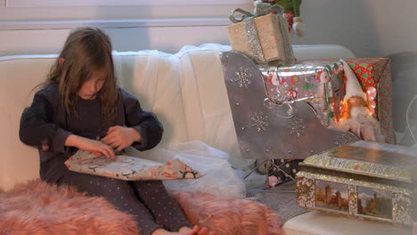 Pretty-Adorable-child-girl-excitedly-unwraps-Christmas-gift