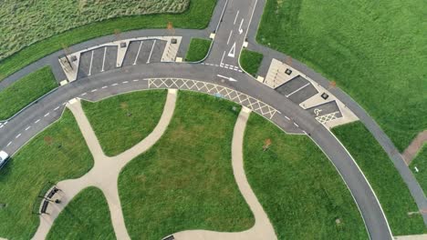 Circular-design-aerial-view-above-ornamental-landscaped-cemetery-garden-with-parking-around-outside