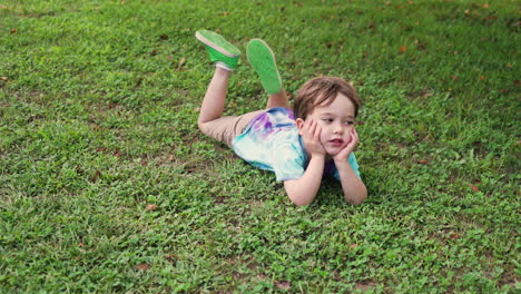 Still-shot-of-an-isolated-american-bored-child-lying-on-the-grass-ground