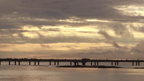 Ein-Dramatischer-Sonnenaufgang-Am-Morgen-Mit-Blick-Auf-Den-Panamakanal-Und-Die-Ferne-Brücke-Cinta-Costera,-Die-Morgensonne-Beleuchtet-Die-Schweren-Tropischen-Regenwolken-Mit-Wunderschönen-Goldenen-Farben,-Panama-City
