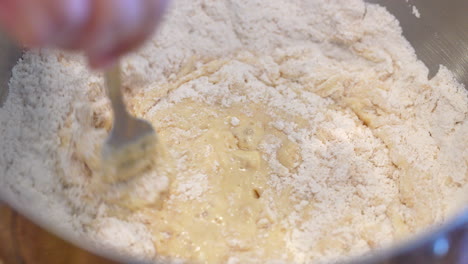 Mixing-flour-into-the-wet-ingredients-to-make-dough---slow-motion-stirring-with-a-fork