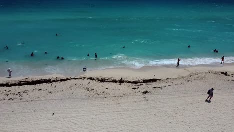 Gente-Nadando-En-El-Mar-Caribe-Al-Mediodía-Y-Olas-Rompiendo-En-La-Costa