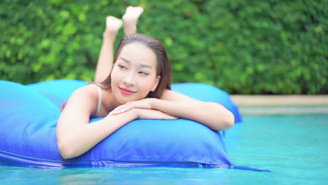 Asian-woman-floating-on-inflatable-mattress-in-a-swimming-pool---close-up