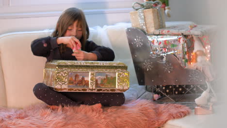 Surprised-and-Excited-young-girl-opening-Box-with-presents-in-front-of-Christmas-decoration-with-gifts-and-packages-on-Santa-sledge