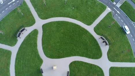 Circular-design-aerial-view-above-ornamental-walkway-cemetery-garden-with-parking-around-outside