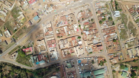 Top-down-aerial-of-traffic-driving-through-a-small-town-in-Kenya