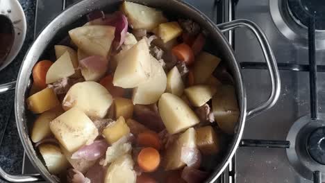 Top-down-view-preparation-of-steaming-stirring-stew-pot-cooking-on-kitchen-stove