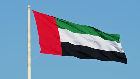 4k-60fps:-La-Bandera-De-Los-Emiratos-árabes-Unidos-Ondeando-En-El-Aire,-El-Cielo-Azul-De-Fondo,-El-Símbolo-Nacional-De-Los-Emiratos-árabes-Unidos
