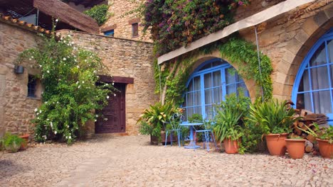 Wunderschöne-Farbenfrohe-Mittelalterliche-Terrasse-Mit-Pflanzen,-Patio-Und-Riesigen-Blauen-Fenstern-Mit-Mediterraner-Atmosphäre