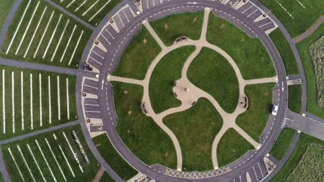Circular-design-aerial-view-above-ornamental-landscaped-cemetery-garden-with-parking-around-outside-slow-left-rotate