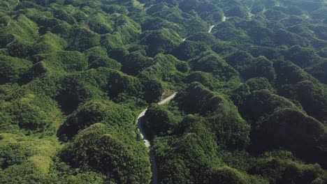 Aerial-drone-view-of-cars-on-a-road,-in-middle-of-jungle-and-hills,-in-Los-Haitises-National-Park,-Dominican-Republic