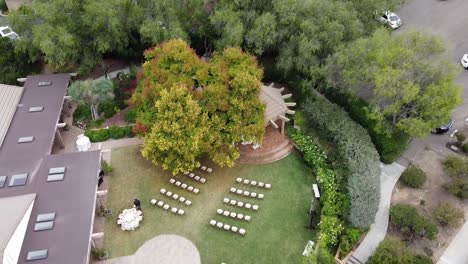Luftaufnahme-Einer-Hochzeitsfeier-Im-Freien-Mit-Weißen-Stühlen-Auf-Einem-Grünen-Rasen