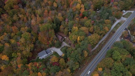Aerial-View,-Cars-on-New-Hampshire-Countryside-Road,-Houses-in-Colorful-Forest