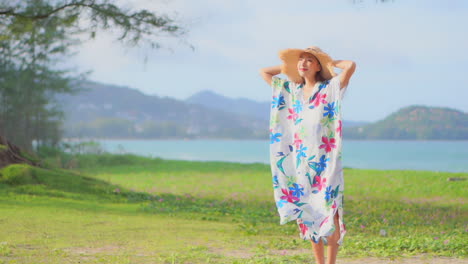 A-pretty-young-woman's-colorful-caftan-flutters-in-the-sea-breeze-as-she-walks-through-the-grass-toward-the-camera