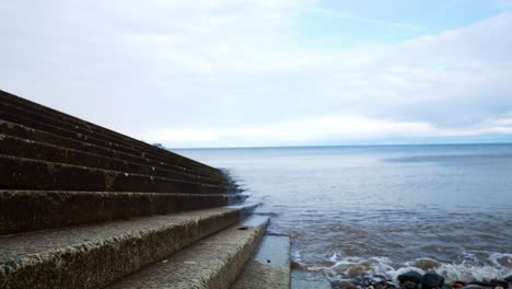 Waves-washing-against-concrete-boat-landing-steps-leading-to-ocean-water-descending-right-shot