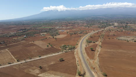 Aerial-dolly-of-a-white-car-driving-over-a-single-road-through-an-amazing-landscape-in-rural-Kenya
