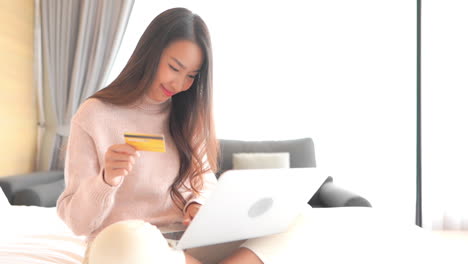 Young-Pretty-Asian-Woman-Shopping-Online,-Using-Laptop-Computer-and-Bank-Credit-Card,-Full-Frame