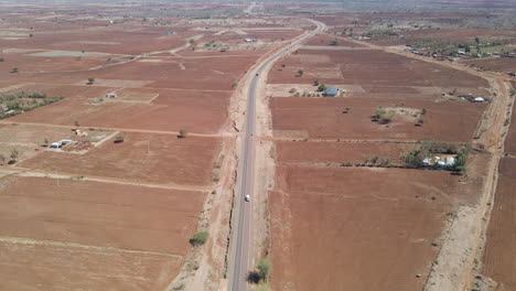 Aerial-of-white-car-driving-over-a-single-road-in-rural-Kenya