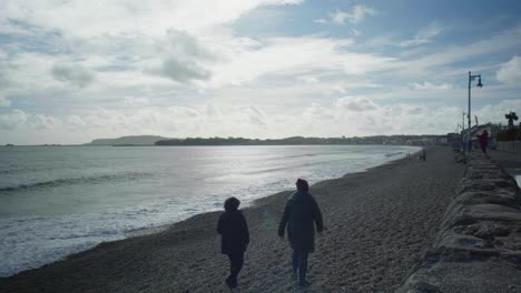 4K-Landscape-shot-of-a-couple-walking-on-the-beach,-on-a-sunny-day