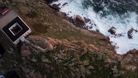 Aerial-bird’s-view-of-lighthouse-with-ocean-cliff-rock-bound-and-waves-crashing,-Spain-north-region-of-Galicia-coastline
