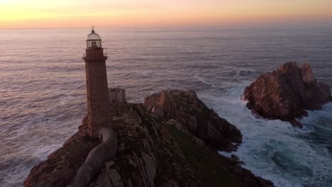 Sunset-aerial-view-of-a-lighthouse-top-of-rock-formation-ocean-cliff,-natural-seascape-in-Spain-Galicia-region-Cabo-vilan
