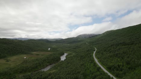 Flying-over-forest-and-road-in-Senja-with-mountains-in-the-background