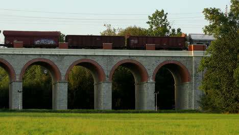A-railway-viaduct-in-the-middle-of-a-field-with-a-freight-train-passing-through-it