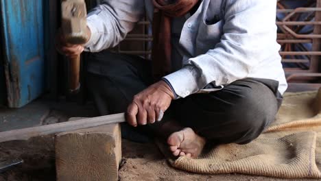 Barefoot-welder-at-work-with-hammer-and-iron-bar-in-Sakhi-Saheli-village,-Rajasthan